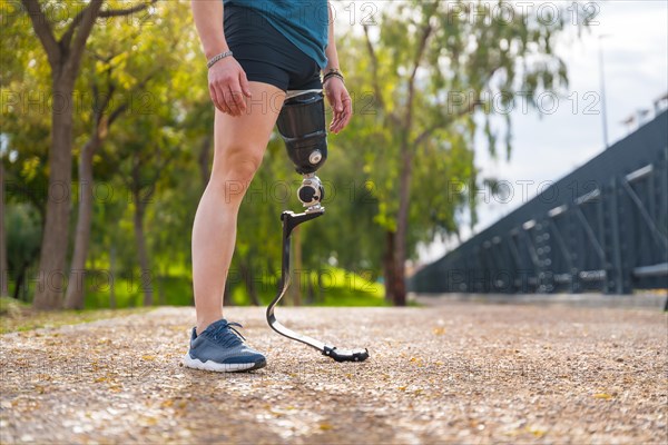 Lower part of the body of an amputee athlete with prosthesis in a park