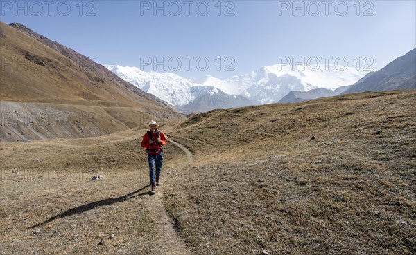 Mountaineers in the Achik Tash valley, in the background glaciated and snow-covered mountain peak Lenin Peak and Peak of the XIX Party Congress of the CPSU, Trans Alay Mountains, Pamir Mountains, Osh Province, Kyrgyzstan, Asia