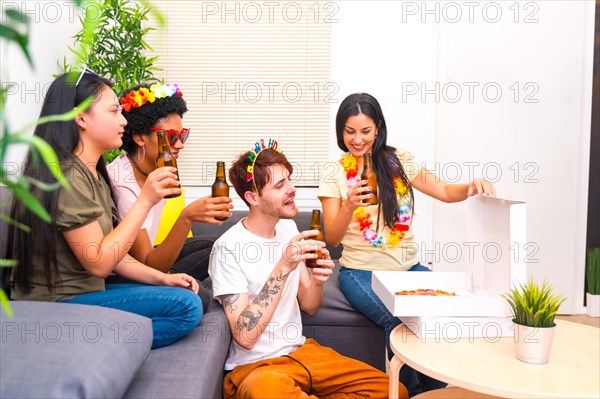 Happy multi-ethnic friends celebrating birthday party at home eating pizza and drinking beer