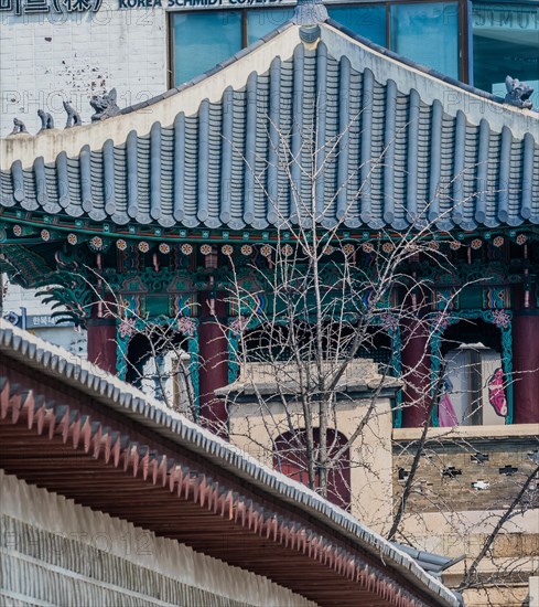 Seoul, South Korea, March 18, 2017:Side gate house at Seoul Palace with tiled roof and traditional architectural design with modern buildings in the background and the palace wall in the foreground, Asia