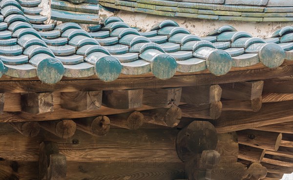 View of tiled roof and wooden beams of an abandoned, unused oriental pavilion in a woodland area in South Korea