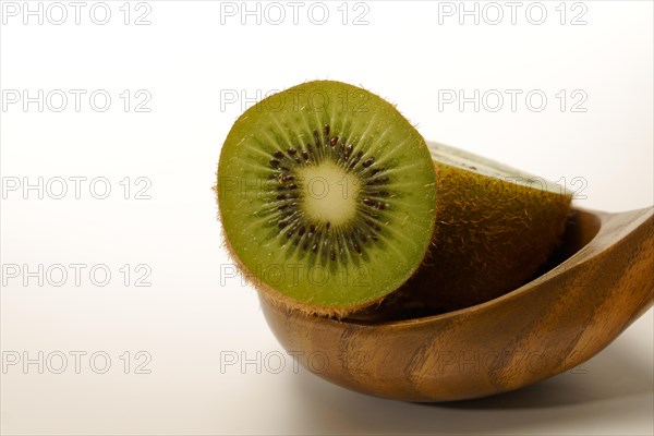 Close-up of a fresh kiwi cut in half in a wooden spoon isolated on a white background and copy space