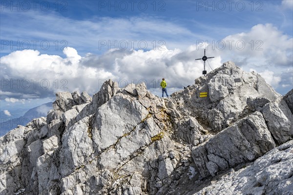 Mountaineer on the rocky summit of the Watzmann Mittelspitze with summit cross, Watzmann crossing, Berchtesgaden National Park, Berchtesgaden Alps, Bavaria, Germany, Europe