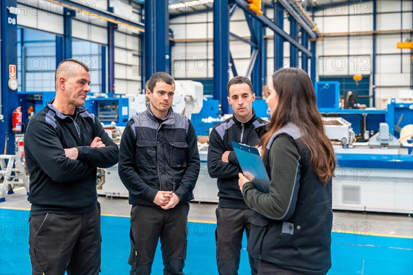 Team of industrial technicians talking standing in the facilities next to machinery