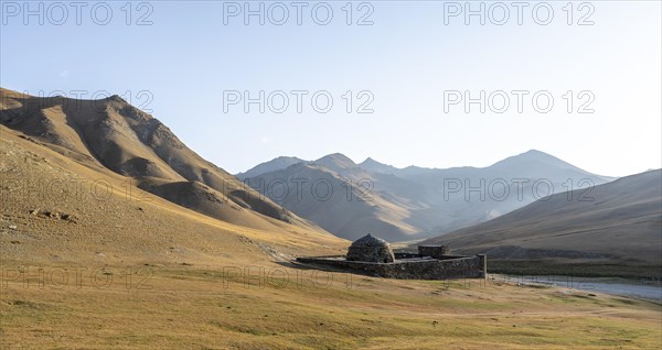 Historic caravanserai Tash Rabat from the 15th century, in the evening light with golden hills, Naryn region, Kyrgyzstan, Asia