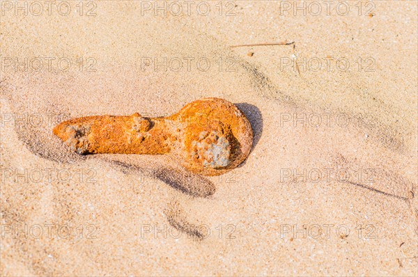 Rusted metal pipe laying in the sand at a beach