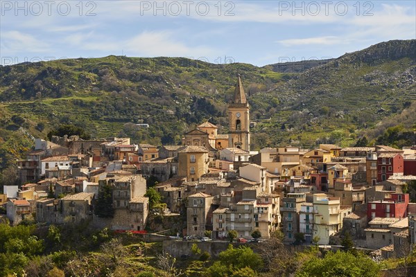 View of a historic town with church tower and surrounding mountains under a clear sky, Novara di Sicilia, Sicily, Italy, Europe