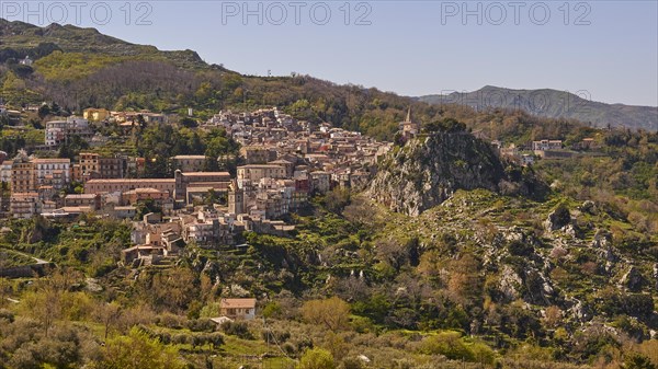 View of a town in the middle of a mountainous landscape with dense vegetation. Novara di Sicilia, Sicily, Italy, Europe