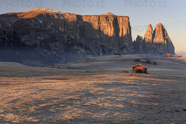 Small huts in the morning light with hoarfrost in front of steep mountains, autumn, Alpe di Siusi, South Tyrol, Dolomites, Italy, Europe