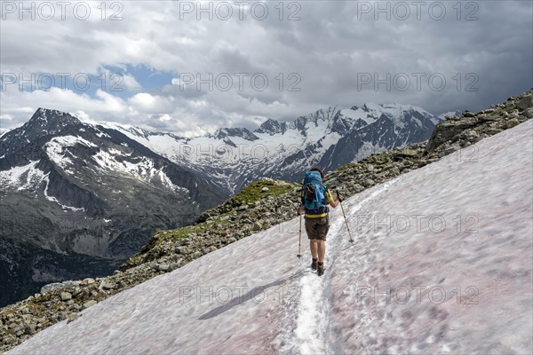 Mountaineer on hiking trail with snow, Berliner Hoehenweg, mountain landscape with glaciated peaks Hochfeiler and Hoher Weisszint, Zillertal Alps, Tyrol, Austria, Europe