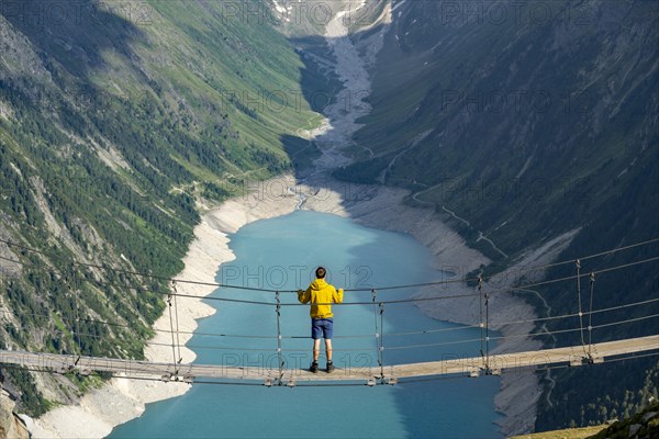 Mountaineers on a suspension bridge, picturesque mountain landscape near the Olpererhuette, view of turquoise-blue lake Schlegeisspeicher, Berliner Hoehenweg, Zillertal Alps, Tyrol, Austria, Europe