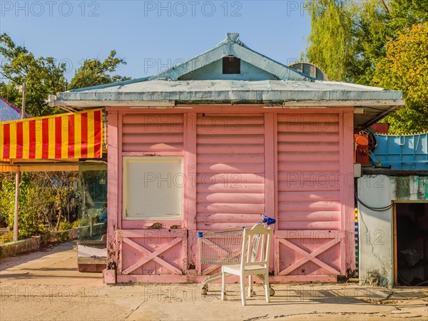 Pink wooden building with yellow and red awning and white roof at bankrupt amusement park