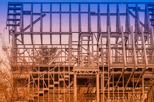 Closeup of metal frame of unfinished building abandoned in wooded countryside on an overcast day