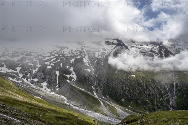 View into the valley of Schlegeisgrund, snow-covered cloudy mountains with Pfitscher ridge and glacier Schlegeiskee, mountain streams as waterfalls on a mountain slope, Furtschaglhaus, Berliner Hoehenweg, Zillertal, Tyrol, Austria, Europe