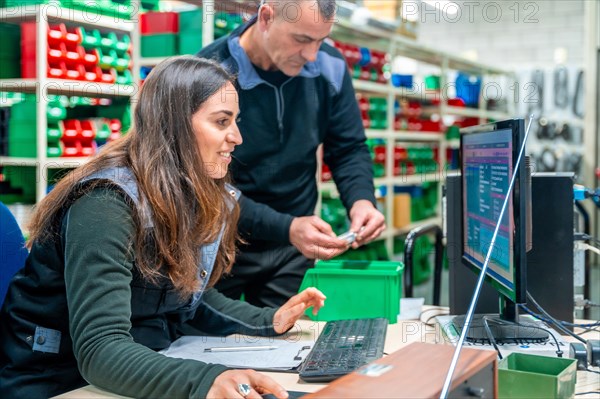 Two male and female workers using computer to do inventory in a logistic center