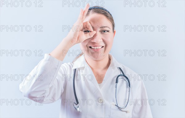 Young female doctor approving with finger on isolated background. Cheerful female doctor gesturing approval isolated