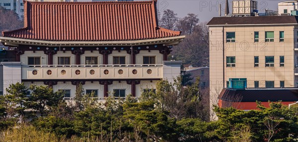 Daejeon, South Korea, March 13, 2017: Building with classical oriental styling with red clay tiled roof, metal mesh windows next to an old, yet modern concrete block building, Asia