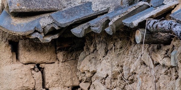 Closeup of a mud brick wall with black tile roof fallen into state of disrepair in South Korea