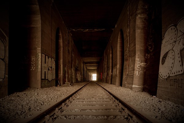 An abandoned railway tunnel, symmetrical with rails and side walls full of graffiti, former Rethel railway branch, Lost Place, Flingern, Duesseldorf, North Rhine-Westphalia, Germany, Europe