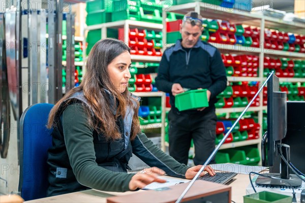 Woman using computer while doing inventory in a logistics modern factory