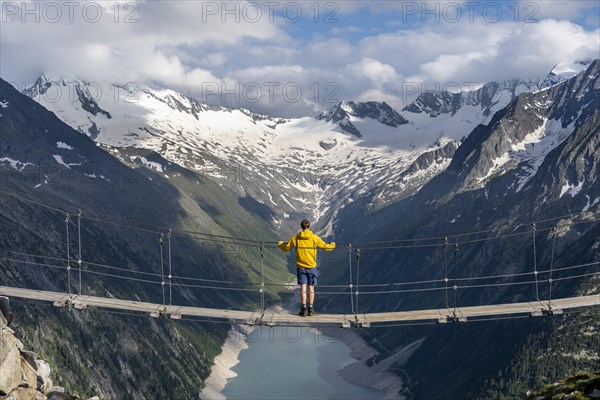 Mountaineers on a suspension bridge, picturesque mountain landscape near the Olpererhuette, view of turquoise-blue lake Schlegeisspeicher, glaciated rocky mountain peaks Hoher Weisszint and Hochfeiler with glacier Schlegeiskees, Berliner Hoehenweg, Zillertal Alps, Tyrol, Austria, Europe