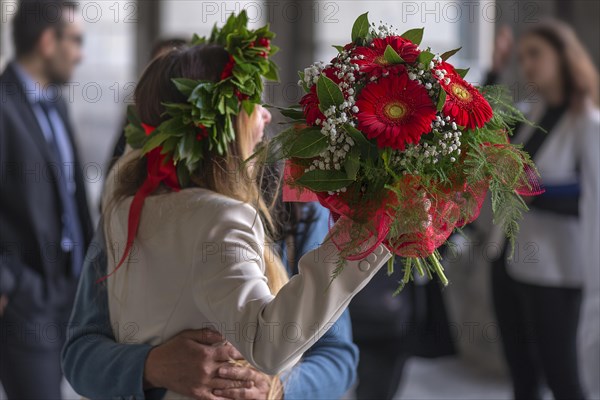Joyful graduate of the University of Genoa with traditional laurel wreath and red ribbon and bouquet of flowers, Genoa, Italy, Europe