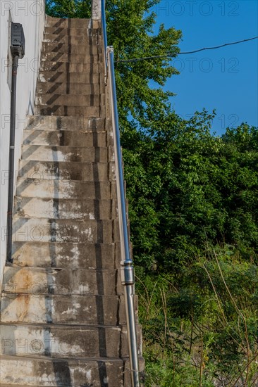 Outside staircase going up to roof of white field in field under blue sky