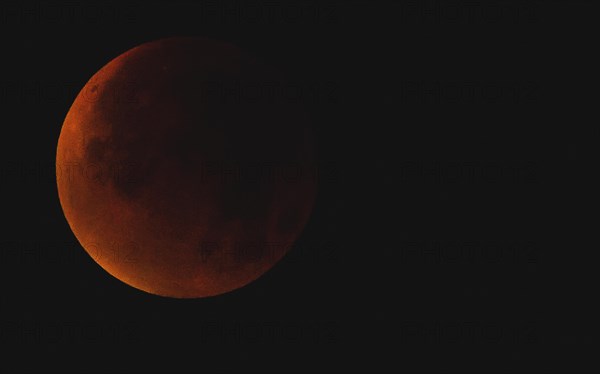 A reddish moon during a total lunar eclipse in the dark night sky, Haan, North Rhine-Westphalia, Germany, Europe