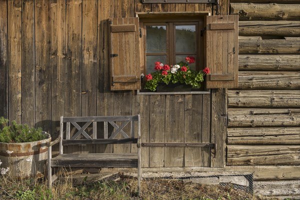 Alpine hut with wooden bench and window with shutters and geraniums, Alpe di Siusi, South Tyrol, Italy, Europe