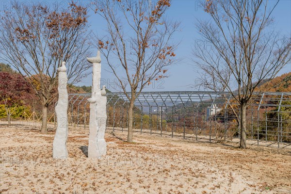 Stone carved ducks on vertical plinths in wilderness park with trees in fall colors