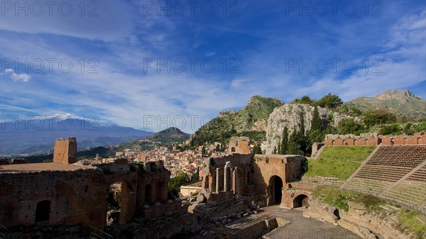 Ancient amphitheatre with ruins in front of a city silhouette and Mount Etna in the background, Taormina, Eastern Sicily, Sicily, Italy, Europe