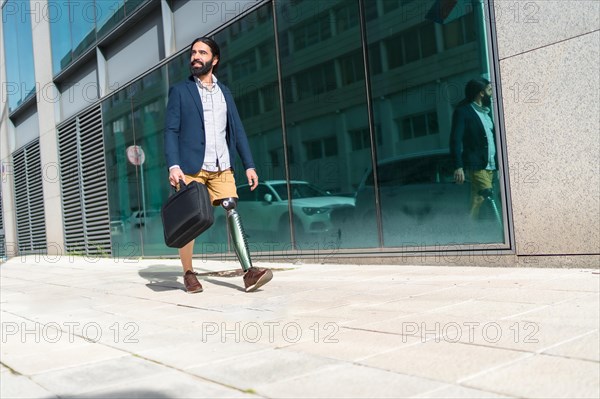 Businessman with prosthetic leg carrying a laptop bag walking along the street