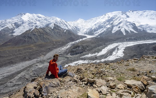 Mountaineer at Traveller's Pass with view of impressive mountain landscape, high mountain landscape with glacier moraines and glacier tongues, glaciated and snow-covered mountain peaks, Lenin Peak and Peak of the XIX Party Congress of the CPSU, Trans Alay Mountains, Pamir Mountains, Osh Province, Kyrgyzstan, Asia