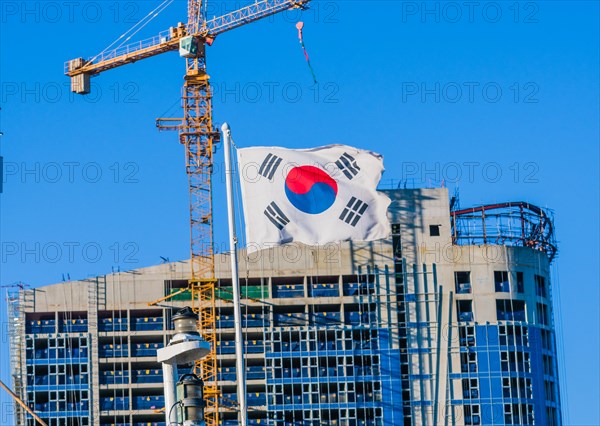Korean flag on flying from a ship with a construction crane attached to a building under construction