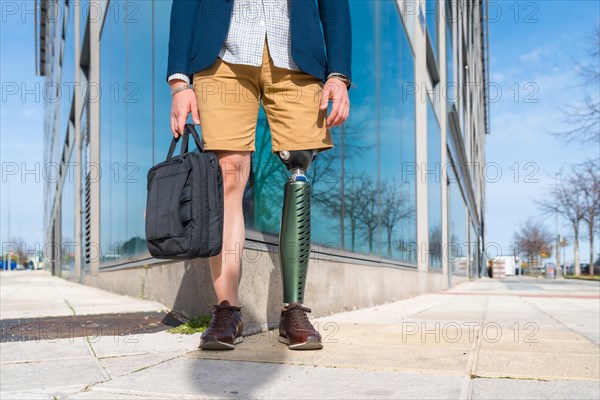 Lower part of an unrecognizable businessman with prosthetic leg standing in the city