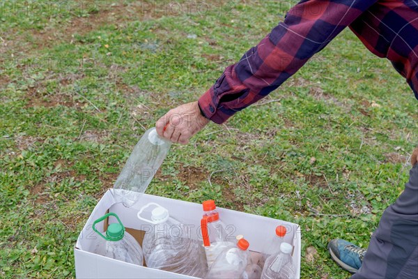 Man collecting empty plastic bottles in the field to recycle, concept of ecology and respect for the environment