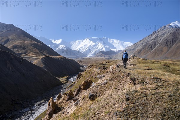 Hiker at the valley with river Achik Tash between high mountains, mountain landscape with peak Pik Lenin, Osh province, Kyrgyzstan, Asia