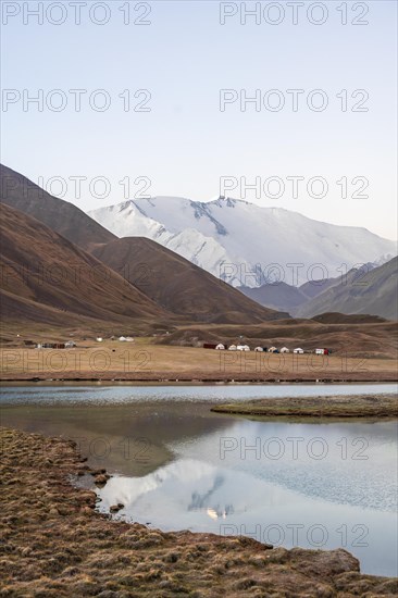 Yurts, mountains reflected in a small mountain lake, Pik Lenin, Trans Alay Mountains, Pamir Mountains, Osh Province, Kyrgyzstan, Asia