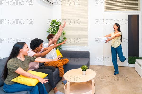 Happy friends receiving a delivery pizza at home while sitting in the sofa