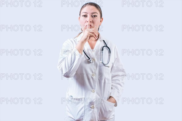 Female doctor making silence gesture isolated. Beautiful female doctor silencing and looking at the camera