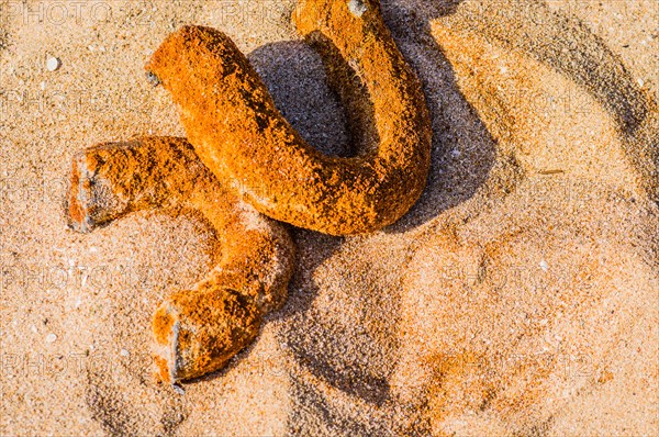 Rusted metal pipe laying in the sand at a beach
