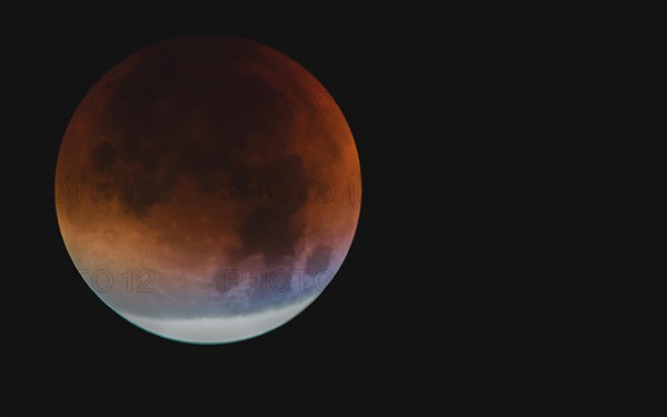 A moon with visible orange and blue tones during a partial lunar eclipse, Haan, North Rhine-Westphalia, Germany, Europe