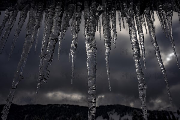 Icicle on gutter in front of dark sky, Balderschwang, Oberallgaeu, Bavaria, Germany, Europe