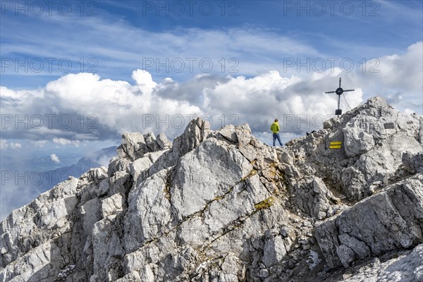 Mountaineer on the rocky summit of the Watzmann Mittelspitze with summit cross, Watzmann crossing, Berchtesgaden National Park, Berchtesgaden Alps, Bavaria, Germany, Europe