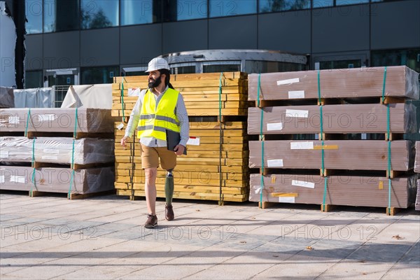 Engineer with prosthetic leg walking along the street next to the construction site