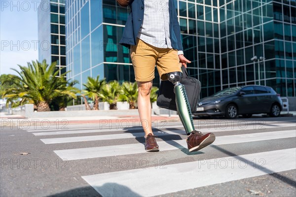 Unrecognizable businessman with prosthetic leg walking in the city