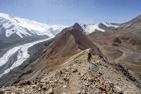 Mountaineer at Traveller's Pass with view of impressive mountain landscape, high mountain landscape with glacier moraines and glacier tongues, glaciated and snow-covered mountain peaks, Lenin Peak, Trans Alay Mountains, Pamir Mountains, Osh Province, Kyrgyzstan, Asia