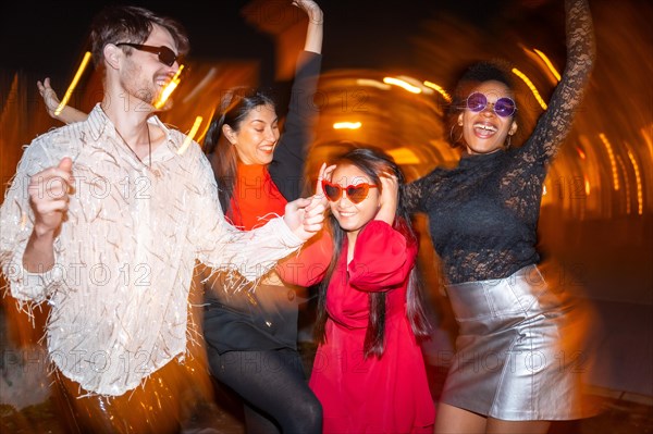 Night photo with flash and motion of four multi-ethnic friends partying in the street