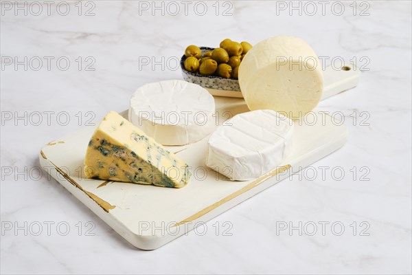 Pieces of brie, camembert, goat cheese and cheese with blue mold on wooden board