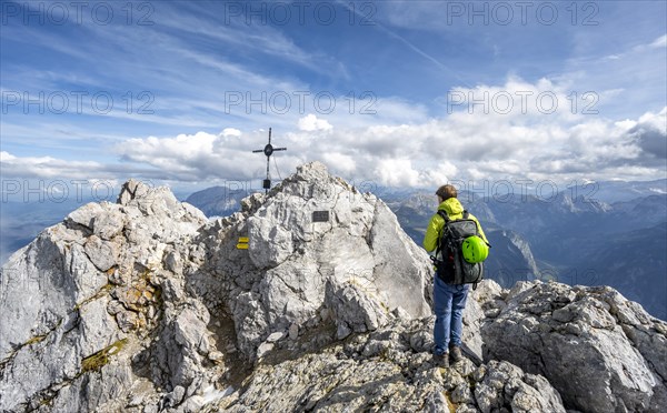 Mountaineer on the rocky summit of the Watzmann Mittelspitze with summit cross, Berchtesgaden National Park, Berchtesgaden Alps, Bavaria, Germany, Europe
